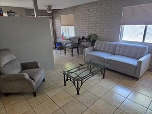 A living room with a grey sofa, a glass coffee table, and a grey armchair. - Peaceful 2-bedroom condo with AC in sunny Tucson (Tucson)