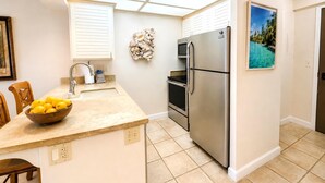 Una cocina con isla central, electrodomésticos de acero inoxidable, microondas y un cuadro en la pared.