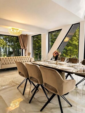 Un espace repas moderne avec une grande table dressée pour six personnes, entourée de fauteuils confortables.