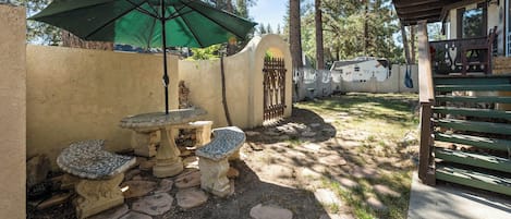 A patio area with stone tables and benches, a green umbrella, and a flag.