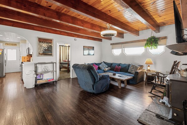 A spacious living area with a wooden ceiling, a sofa set, a coffee table, and a fireplace.
