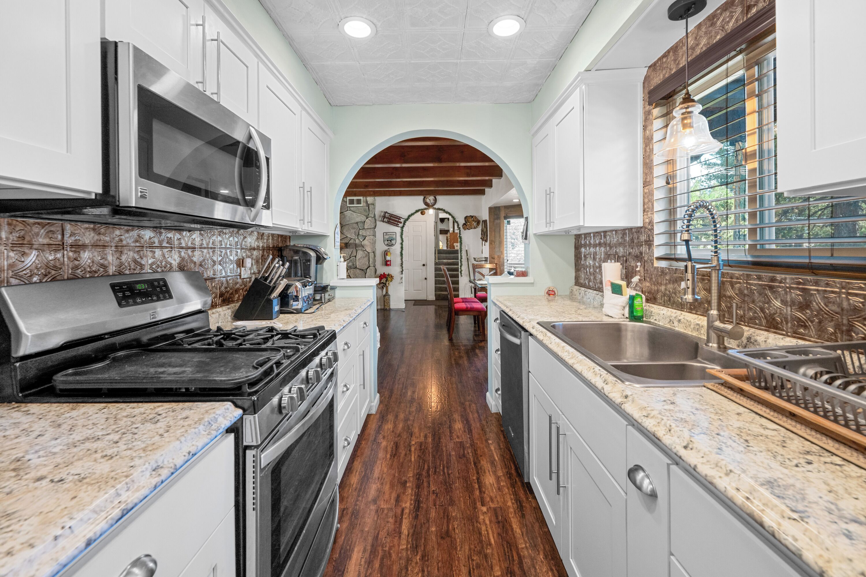 A kitchen with a stove, microwave, and sink.