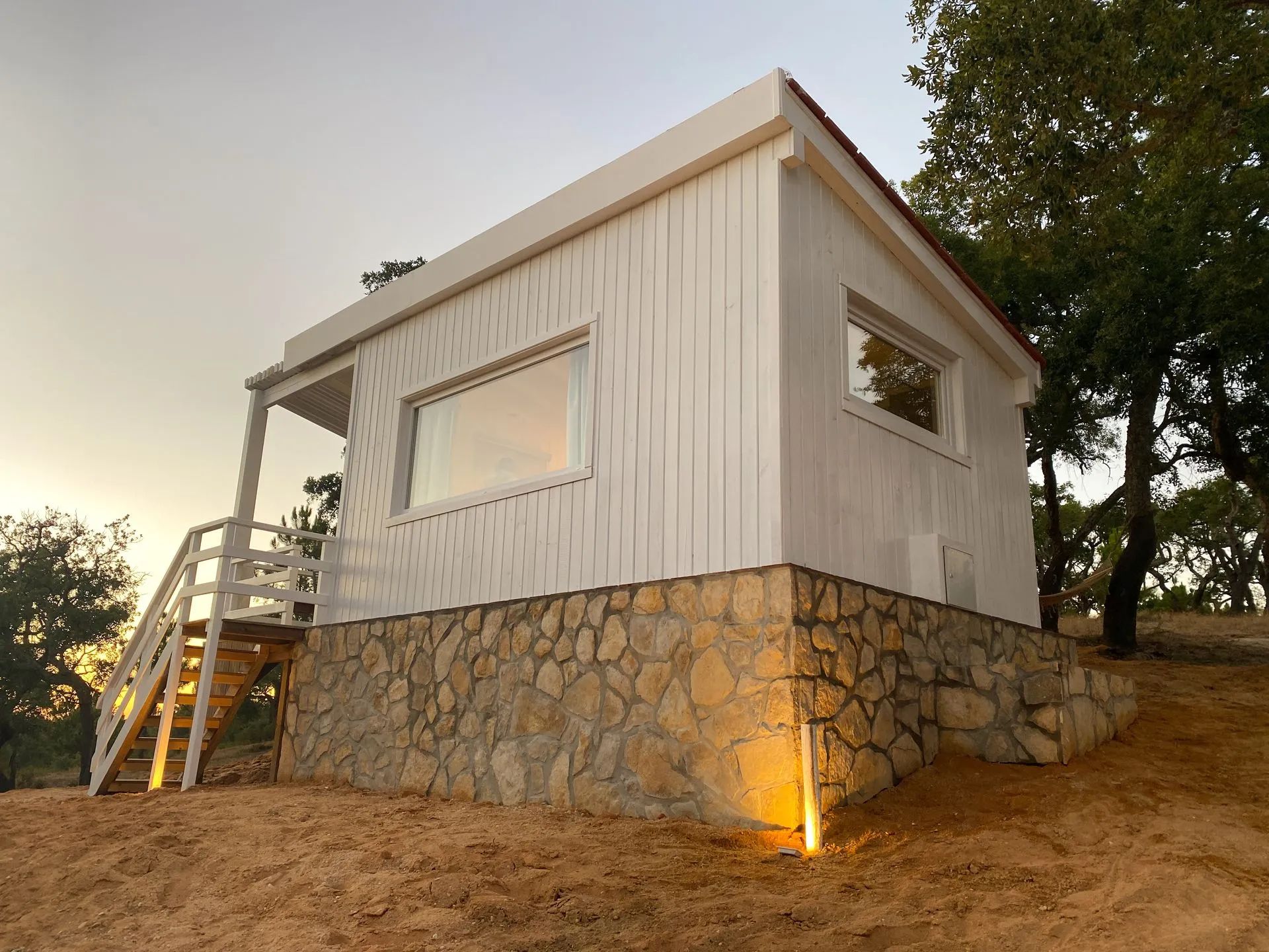 A modern house with a stone foundation and a white exterior.