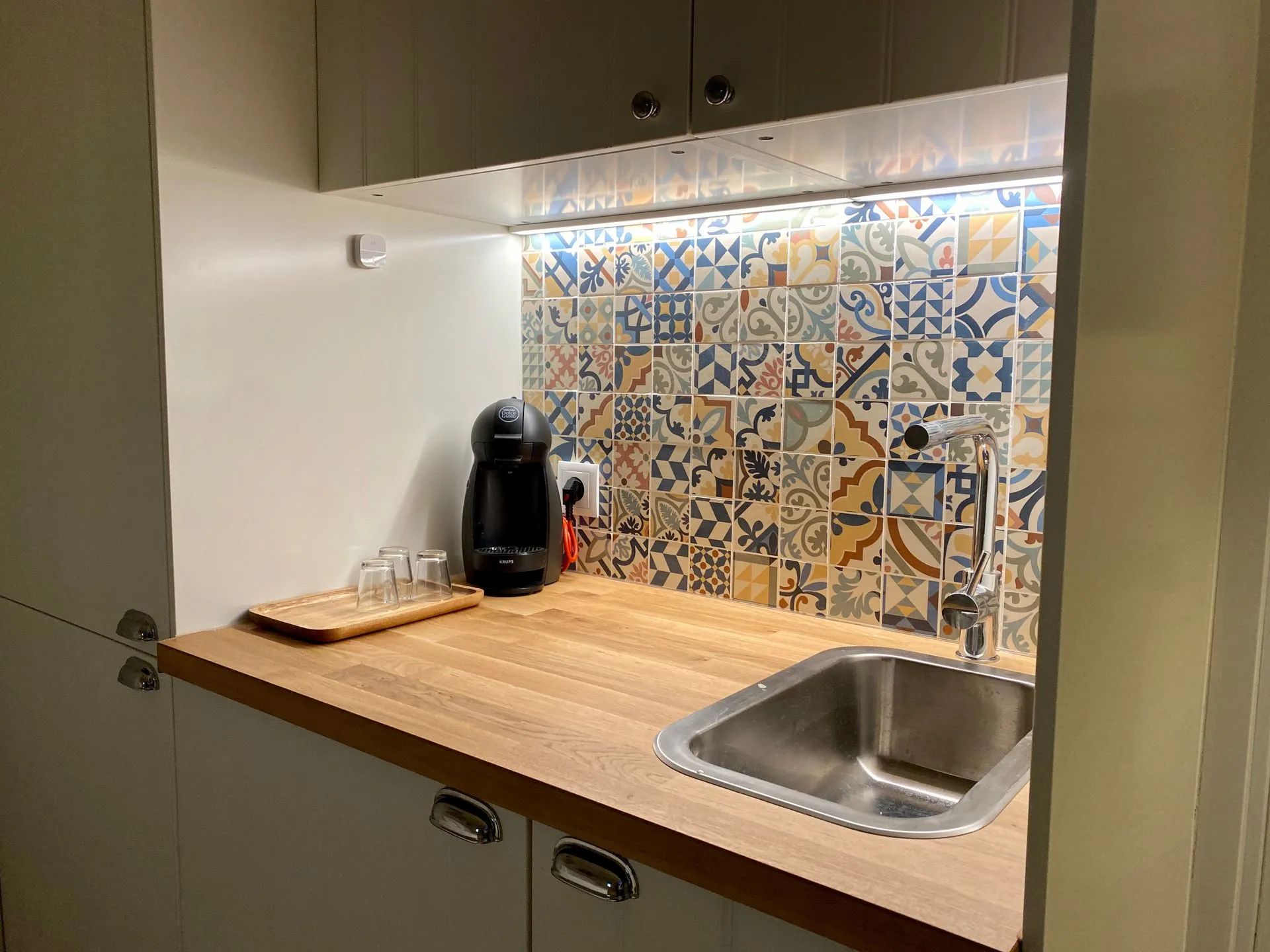 Una cocina compacta con encimera de madera, cafetera y lavabo.