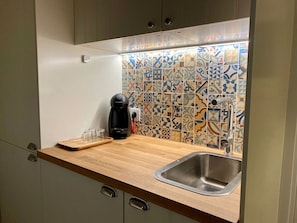 Una cocina compacta con encimera de madera, cafetera y lavabo.