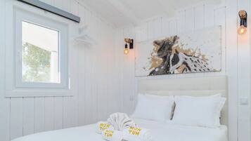 Una habitación de hotel con una cama, una ventana y un cuadro colgado en la pared.