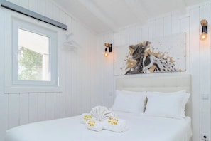 Habitació d'hotel amb un llit, una finestra i un quadre penjat a la paret.
