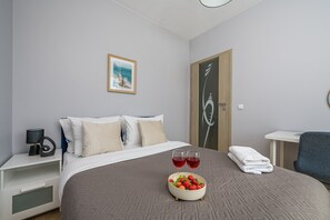 A hotel room with a bed, a bedside table with a lamp, a framed picture on the wall, and a door with a decorative design. - Lumina 2-room Apart with Balkony & Metro (Warszawa)