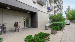 Un edificio moderno con entrada vigilada, bicicletas estacionadas afuera y un letrero de no estacionamiento.
