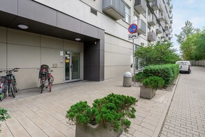 A modern building with a gated entrance, bicycles parked outside, and a no parking sign. - Lumina 2-room Apart with Balkony & Metro (Warszawa)