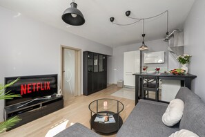 A modern living room with a flat-screen TV, a sofa, a coffee table, and a dining area with a table and chairs. - Lumina 2-room Apart with Balkony & Metro (Warszawa)