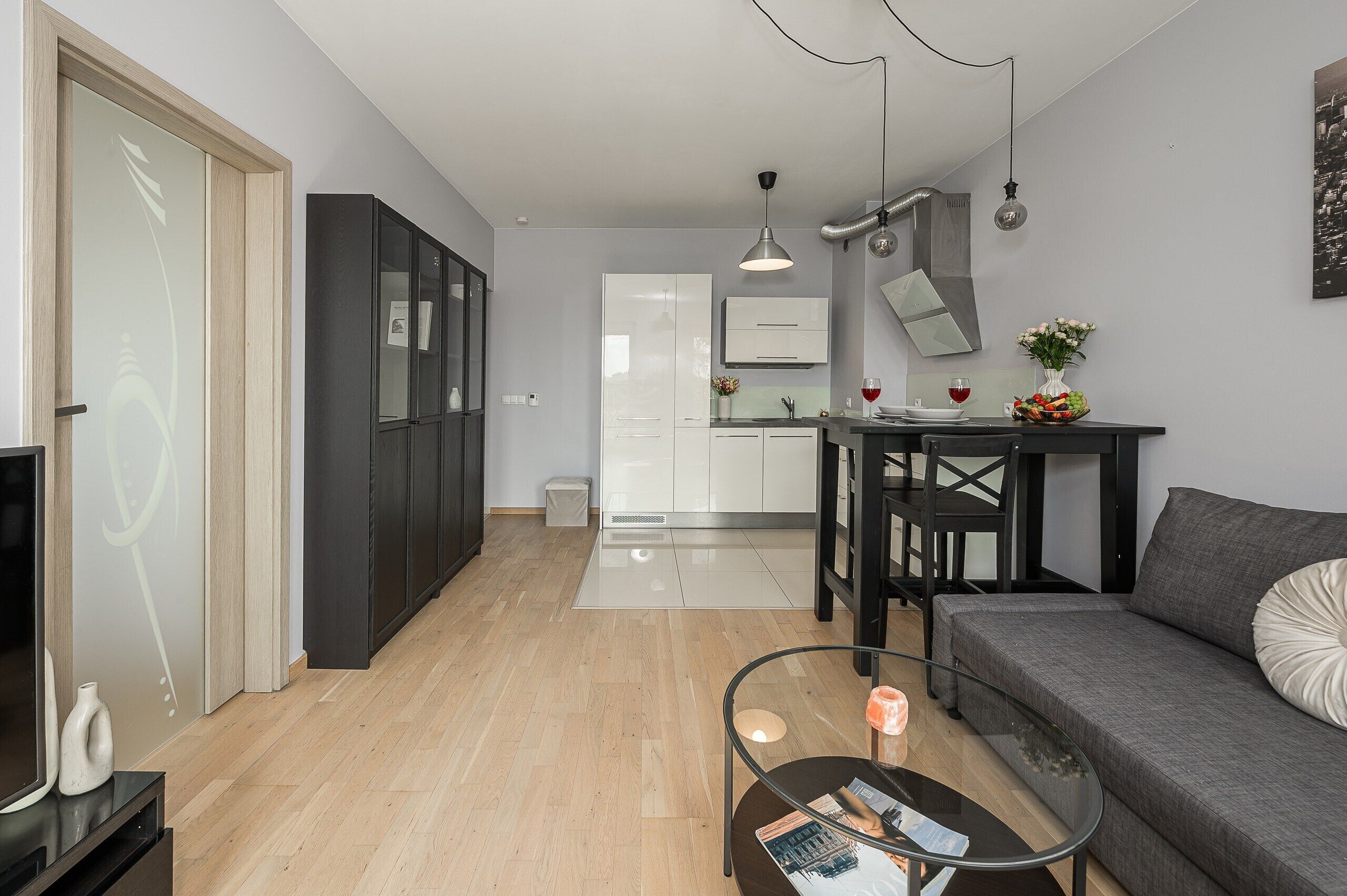 Una sala de estar moderna con un sofá, una mesa de centro de vidrio y una zona de comedor con una mesa y sillas.