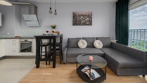 Un espacio habitable moderno con cocina, comedor y un amplio ventanal con vistas a la ciudad.