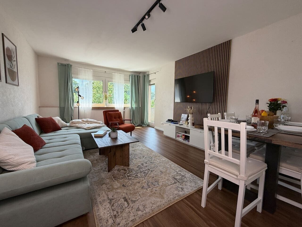Ein stilvolles Wohnzimmer mit einer Couch, einem Couchtisch und einem Essbereich mit Stühlen sowie einem Fernseher.