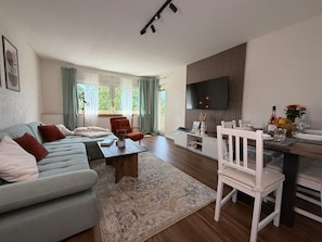 Ein stilvolles Wohnzimmer mit einer Couch, einem Couchtisch und einem Essbereich mit Stühlen sowie einem Fernseher.