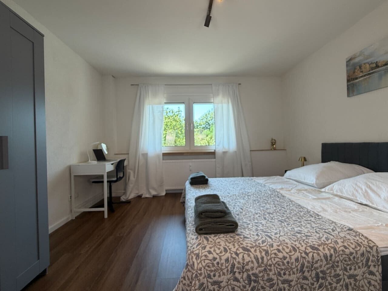Ein Schlafzimmer mit einem Bett, einem Schreibtisch und einem Fenster.