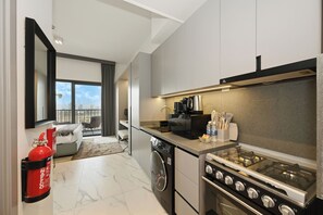 A modern kitchen with a gas stove, a coffee maker, and a view of the city. - Bloomfields Studio in Mag Eye 920 (Dubai)