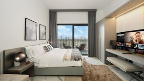 Quarto de hotel moderno com cama, escrivaninha, TV e varanda com vista para a cidade.