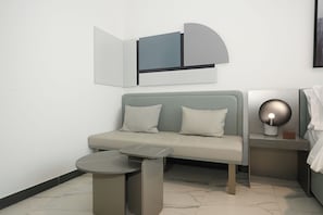 A modern room with a grey sofa, a small round table, and a wall-mounted lamp. - Bloomfields Studio in Mag Eye 920 (Dubai)