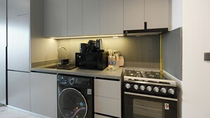 Uma cozinha compacta com máquina de lavar, micro-ondas, fogão a gás e pia.