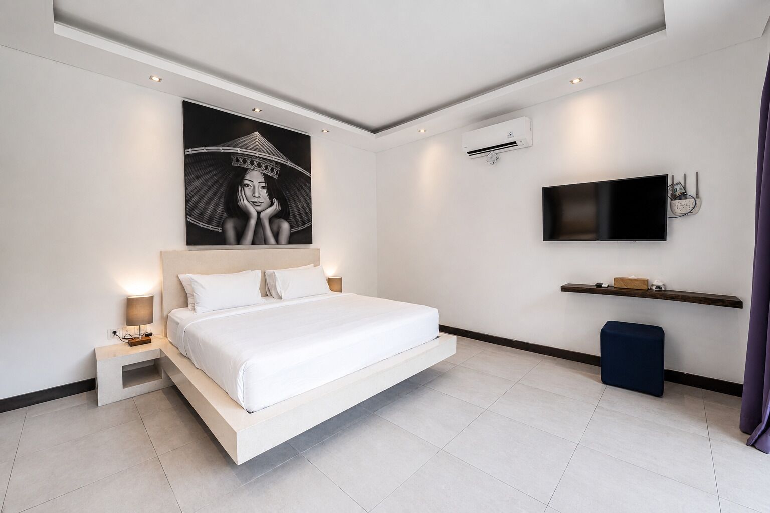 Une chambre moderne dotée d’un grand lit, d’un téléviseur à écran plat, d’un appareil de climatisation et d’une étagère fixée au mur.