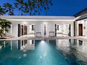 Ein moderner Poolbereich mit klarem Pool, Liegestühlen und einem von Glas umschlossenen Spa-Bereich.