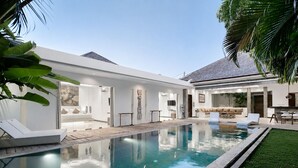 Et moderne hus med swimmingpool, terrasse og velholdt græsplæne.