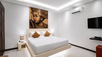 A modern bedroom with a large bed, a flat-screen TV, and a wall-mounted air conditioner.