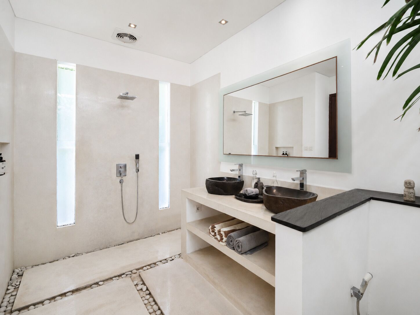 A modern bathroom with a walk-in shower, a large mirror, and a vanity with two sinks.