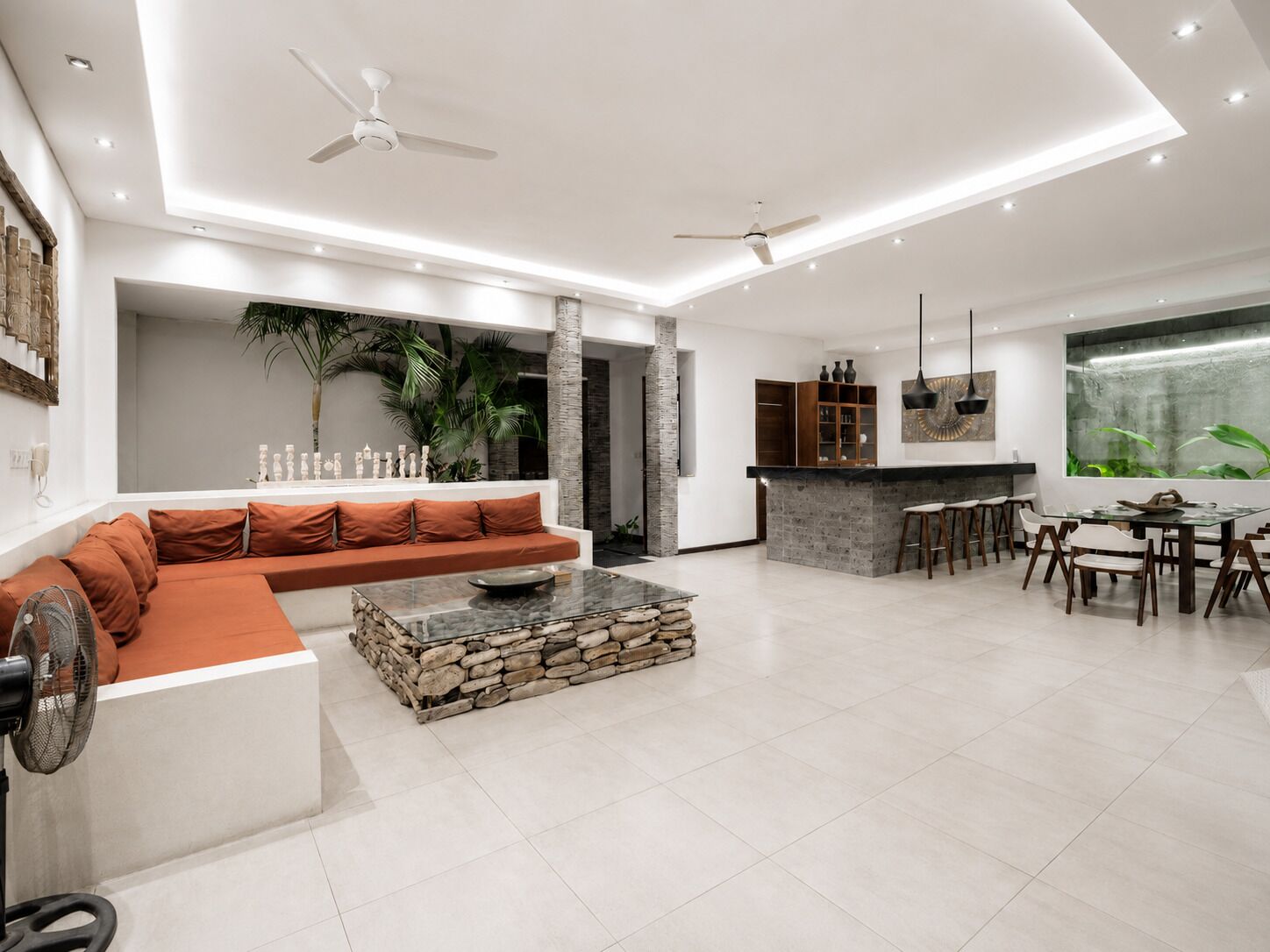 A modern living room with a stone coffee table, a sofa, and a dining area with chairs and a table.