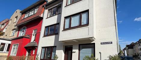 Ein zweistöckiges Gebäude mit weißer Fassade und einem roten Teil auf der linken Seite.