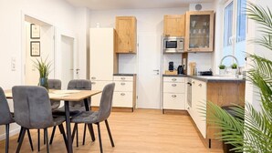 Una cocina moderna con armarios de madera, una mesa de comedor con sillas y un horno empotrado.