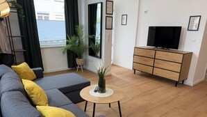 Una sala de estar moderna con un sofá gris, una mesa de centro de madera y un mueble para televisión.