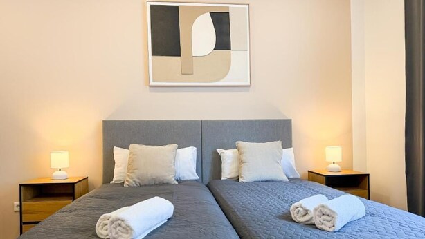 Habitación de hotel con dos camas, un cuadro abstracto grande y lámparas de noche.