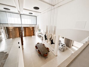 A modern interior with a central table and chairs, a wooden partition, and a hanging light fixture. - Contemporary Elegance - Amelkis Golf Course - Elevator & Hammam (Marrakech)