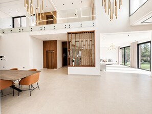A spacious, modern interior with a dining area, a staircase, and large windows. - Contemporary Elegance - Amelkis Golf Course - Elevator & Hammam (Marrakech)
