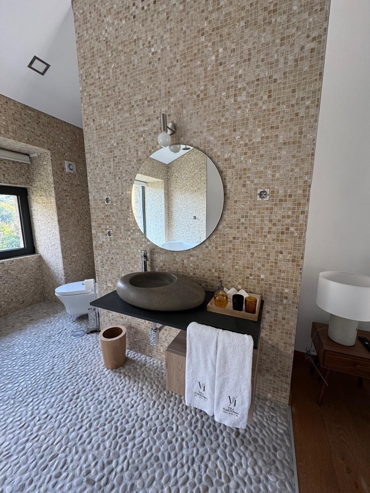 Une salle de bain avec un lavabo rond, un miroir, des toilettes et une baignoire.