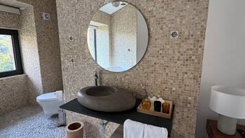 Een badkamer met een rond wastafel, een spiegel, een toilet en een bad.