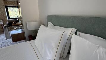 A hotel room with a bed, a nightstand, a lamp, and a window with a view.