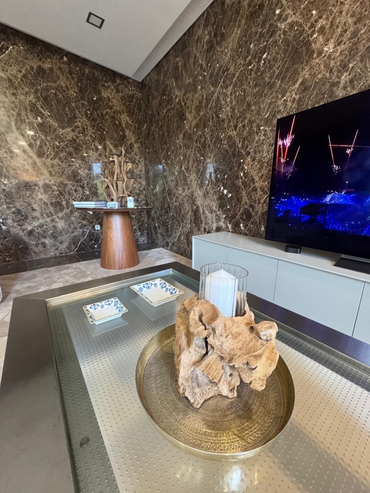 A modern interior with a marble wall, a flat-screen TV, a decorative wooden piece, and a tray with a tissue box.