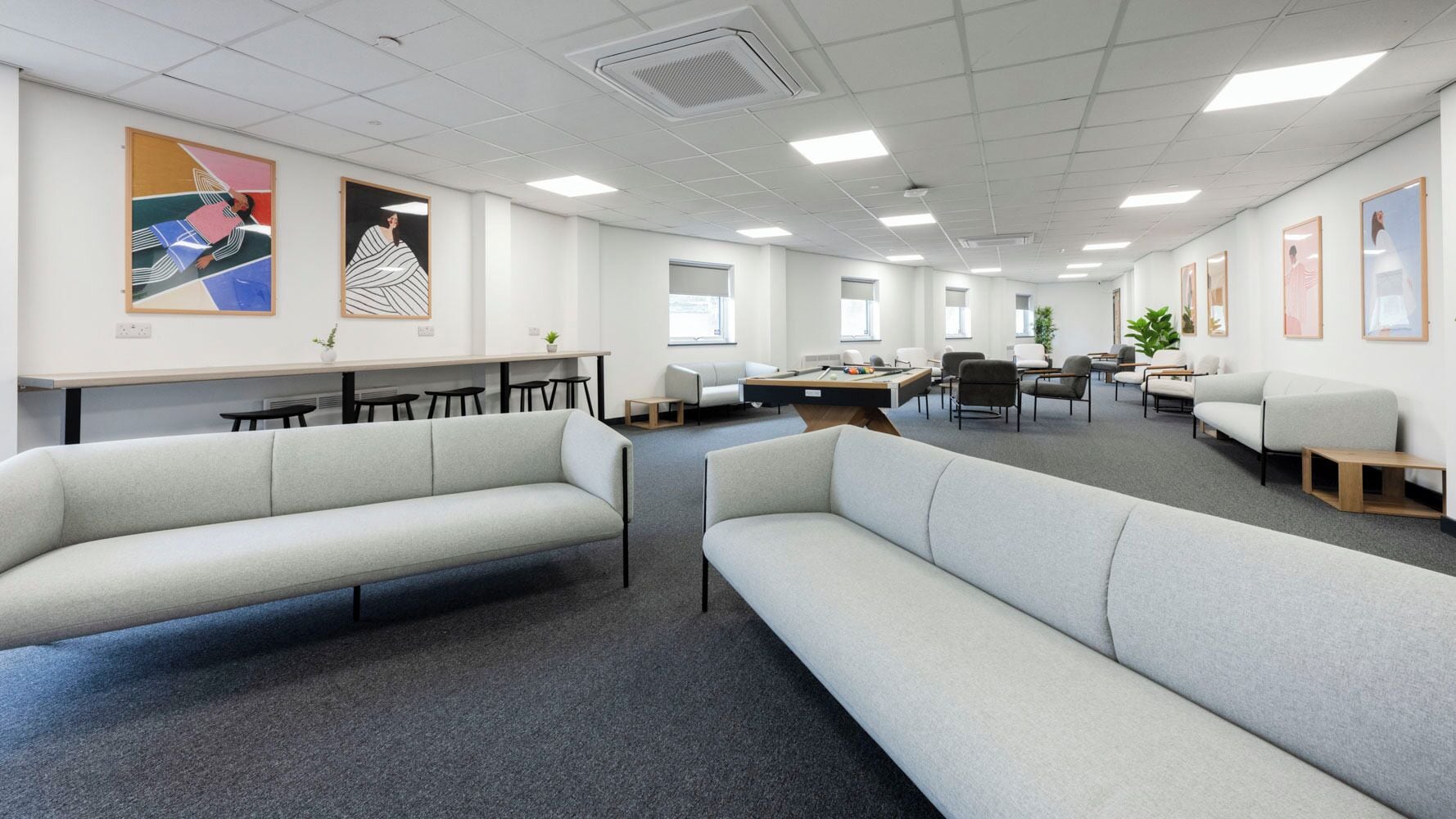 A modern office space with sofas, tables, and artwork on the walls.