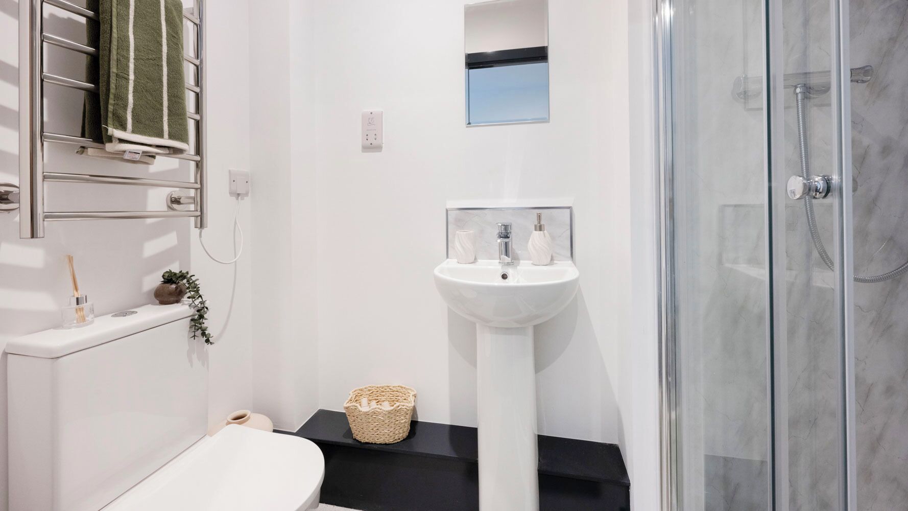 A bathroom with a white sink, a glass shower enclosure, and a towel rack.