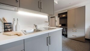 A modern kitchen with a stainless steel sink, wooden cutting board, and utensils. - Student Only Icon House (Stoke-on-Trent)