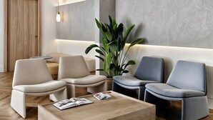 A modern lounge area with sofas, a coffee table, and a potted plant. - Student Only Icon House (Stoke-on-Trent)