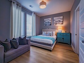 A bedroom with a bed, a nightstand, a dresser, a sofa, and a window with blinds. - Your Nashville home base-comfort close to downtown (Nashville)