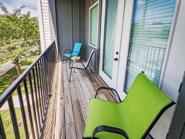 A wooden deck with two chairs, one green and one blue, and a door with a window. - Your Nashville home base-comfort close to downtown (Nashville)