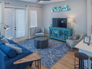 A living room with a blue sofa, a coffee table, a TV on a blue cabinet, and a neon sign on the wall. - Your Nashville home base-comfort close to downtown (Nashville)