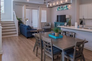 A modern kitchen with a dining area, featuring a wooden dining table, chairs, and a kitchen island with a sink and countertop. - Your Nashville home base-comfort close to downtown (Nashville)