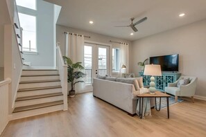 A modern living room with a staircase, a sofa set, a television, and a ceiling fan. - Your Nashville home base-comfort close to downtown (Nashville)