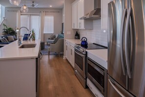 Une cuisine moderne équipée d’appareils électroménagers en acier inoxydable, d’un four encastré et d’un grand réfrigérateur.